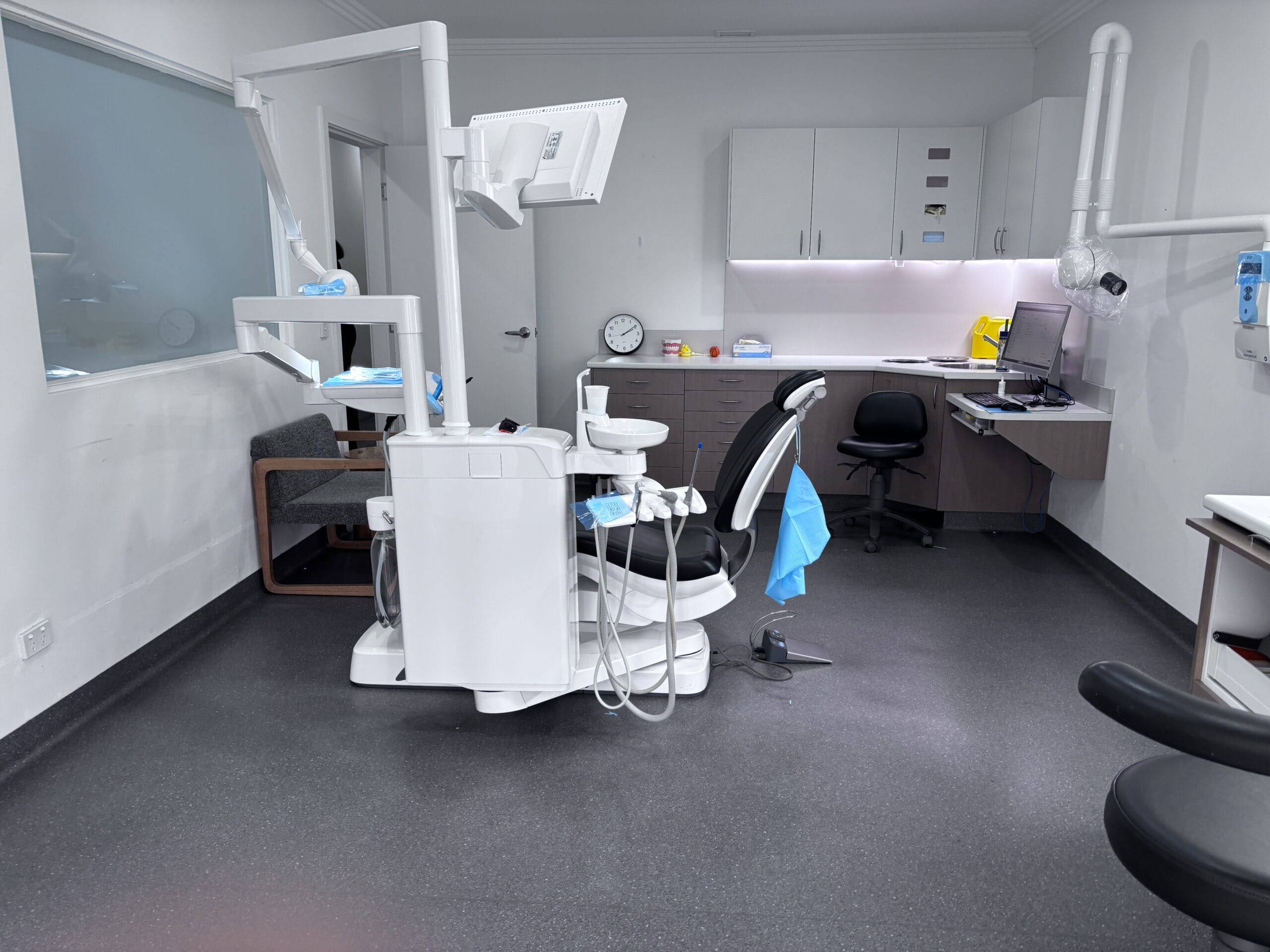A modern, sterile dental treatment room featuring a central reclining patient chair integrated with a white medical equipment unit at No Gaps Dental Randwick.